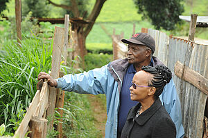 Two people standing by a fence