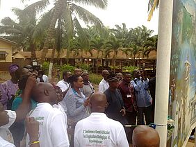 Several people assembled in a square with palm trees.