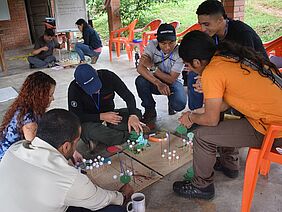 A group of people sitting gathered around a model of a system.