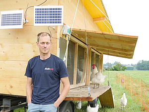 Ein Mann vor einem mobilen Hühnerstall.