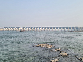 Wasserfläche mit Damm am Horizont.