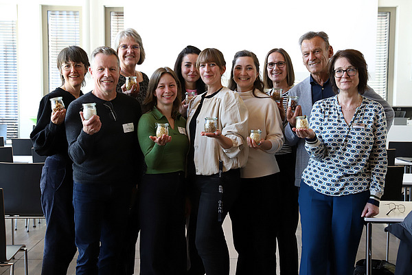 Gruppenfoto, Personen präsentieren kleine Gläser mit verarbeiteten Ackerbohnen und Erbsen.