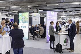 People standing and sitting on various desks with banners around.