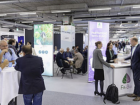 People standing and sitting on various desks with banners around.