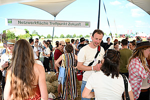 Menschen unter einem Sonnensegel unterhalten sich angeregt.