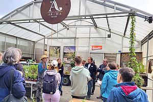 Eine Gruppe von Menschen steht vor einem Gewächshaus.
