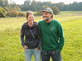 Un homme et une femme, bras dessus bras dessous, dans un pré.