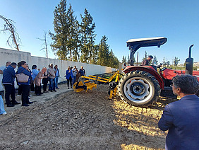 People inspecting a tractor with tillage attachment.