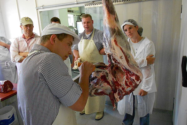 Metzger und Seminarteilnehmer beim Zerteilen von Fleisch