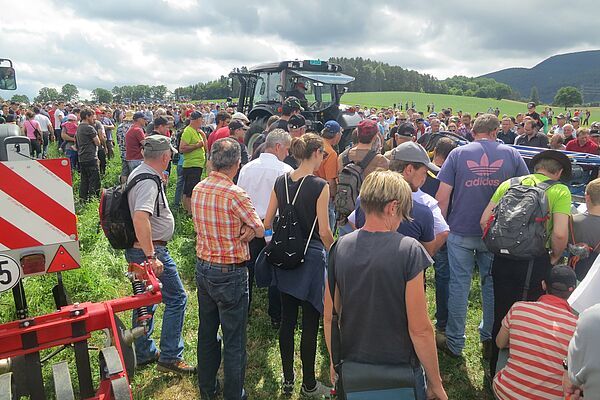 Un groupe de personnes se tient près d'un tracteur.