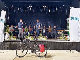 Plusieurs personnes sur une scène, avec un vélo devant