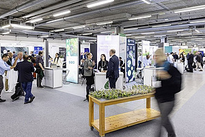 Eine Halle mit Ausstellern und Besuchenden.
