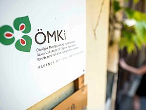 A sign with an ÖMKi logo on a house wall.