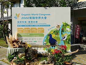 Eine Tafel vor einem Gebäude mit Informationen über den Organic World Congress.
