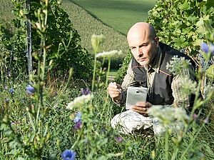 Un homme accroupi dans une prairie.