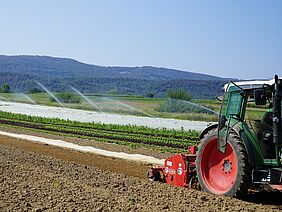 Traktor auf einem Feld mit Bewässerung im Hintergrund