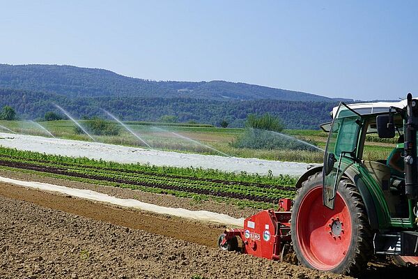 Traktor auf einem Feld mit Bewässerung im Hintergrund