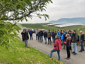 Eine Gruppe Menschen in Obstanlage.