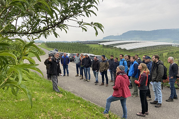 Eine Gruppe Menschen in Obstanlage.
