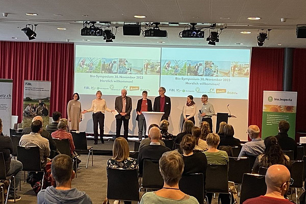 Menschen sitzen in einem Raum und hören einem Vortrag zu.