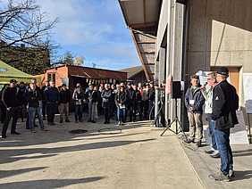 Drei Personen, die zu einer Gruppe Menschen sprechen.