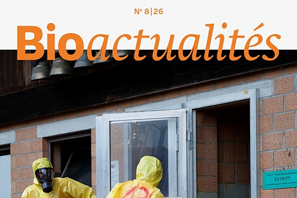 Page de couverture du Bioactualités 8|26: Trois personnes vêtues de combinaisons de protection et portant des masques respiratoires à l'entrée d'une étable.