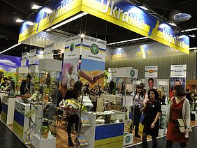 Stand of the Ukraine with the flag's colours blue and yellow, and people attending.