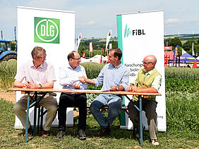 Vier Personen unterzeichnen einen Vertrag