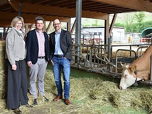 Trois personnes et une vache dans une étable.