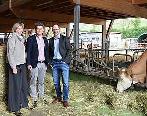 Three people and a cow in a barn.