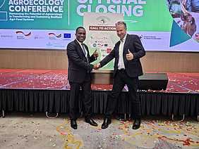 Two men shaking hands and giving a thumbs-up.