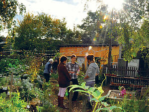 Three persons talking in a garden.