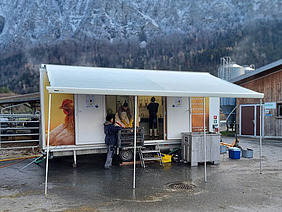 Geöffneter Anhänger auf einem Hofplatz.