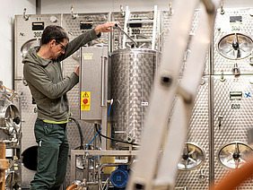 Ein Mann, der an einem Metallfass hantiert. 