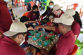 A group of men and women sit around a model of their agroforestry system.