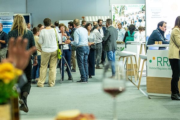 A hall with people at tables, and exhibitors.
