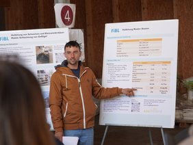 Ein Mann erläutert etwas anhand eines Posters zur Hoftötung.