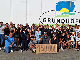 Menschengruppe mit einem Schild, auf dem 150.000 steht.