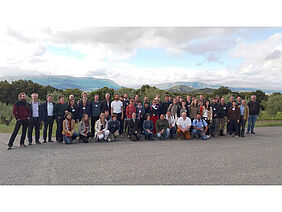 A group of people in front of a hilly landscape.