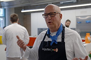 Mann mit Kochschürze in einer Großküche.