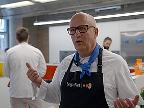 Mann mit Kochschürze in einer Großküche.