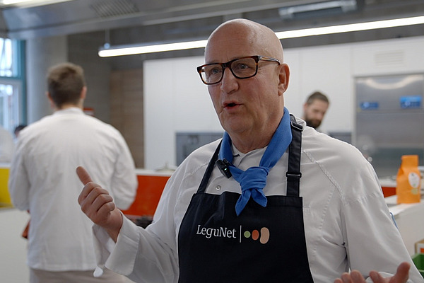 Mann mit Kochschürze in einer Großküche.