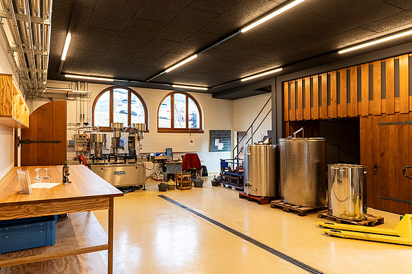 Raum mit Theke, Metallfässern und weiteren Gerätschaften. 