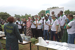 A large group of people standing opposite a woman behind a table