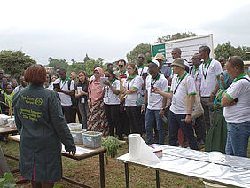 A large group of people standing opposite a woman behind a table