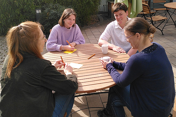 Vier jungen Frauen an einem Tisch im Gespräch. 