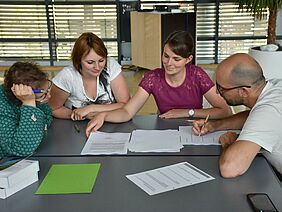 Mehrere Personen studieren Papiere.