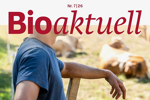Titelseite Bioaktuell 7|26: Ein Mann lehnt an einen Zaun, im Hintergrund befinden sich Kühe.