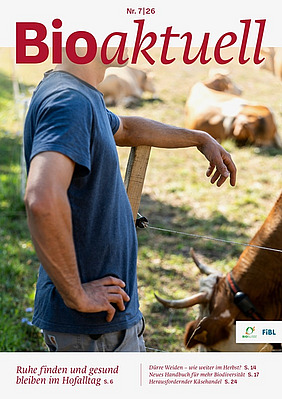 Titelseite Bioaktuell 7|26: Ein Mann lehnt an einen Zaun, im Hintergrund befinden sich Kühe.