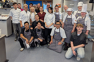 Gruppenfoto mit rund 20 Personen in Kochkleidung.